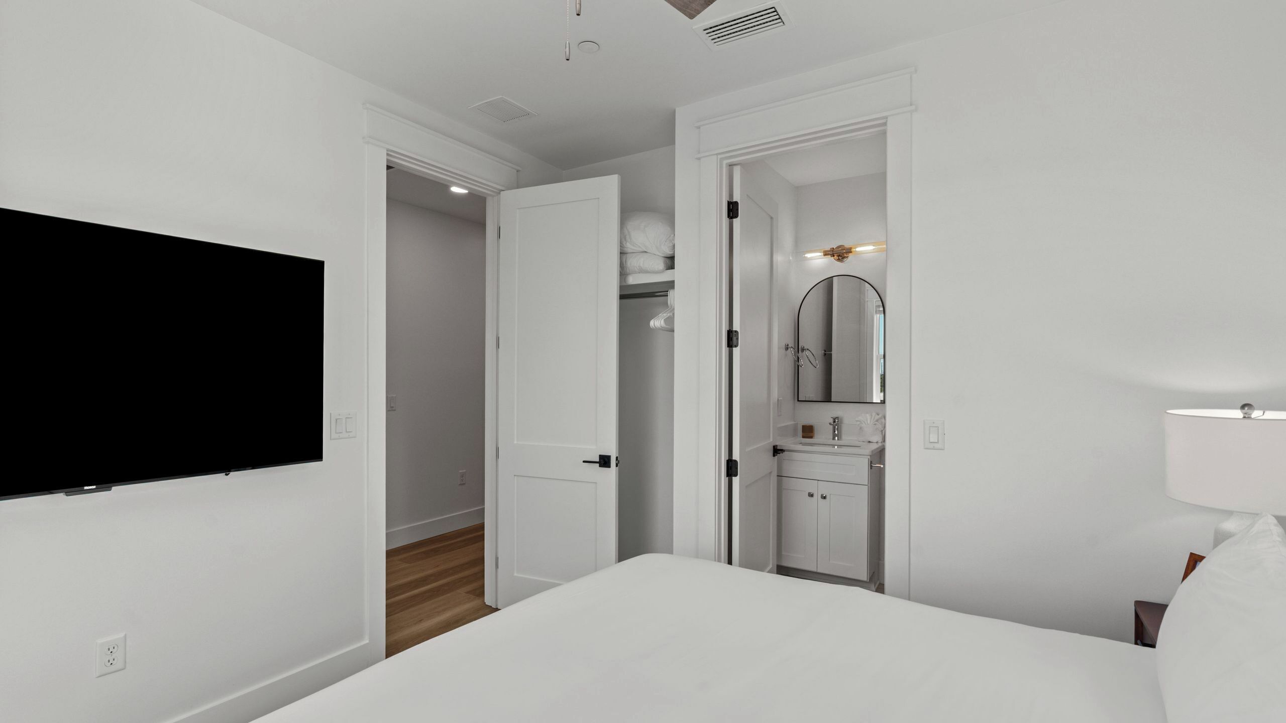 Habitación de hotel con cama, televisión, baño con espejo y vestidor.