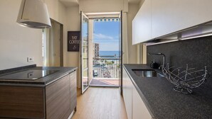 A modern kitchen with a view to the sea, a hanging light fixture, and a metal kitchen rack. - Double One Beach & City (Recco)