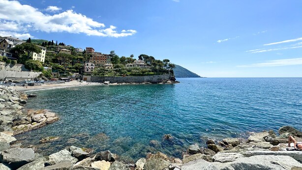 A coastal town with buildings along the shore, clear blue water, and rocky terrain. - Double One Beach & City (Recco)
