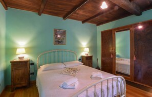 A bedroom with a bed, two bedside tables, a wooden wardrobe, and a ceiling light fixture.