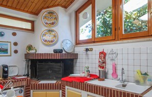 A kitchen with a brick fireplace, a clock, and decorative plates on the wall. - 3 bedroom stunning home in Appignano (Appignano)