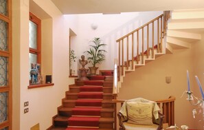 A staircase with red carpeted steps, wooden railings, and a chair with a cushion. - 3 bedroom stunning home in Appignano (Appignano)