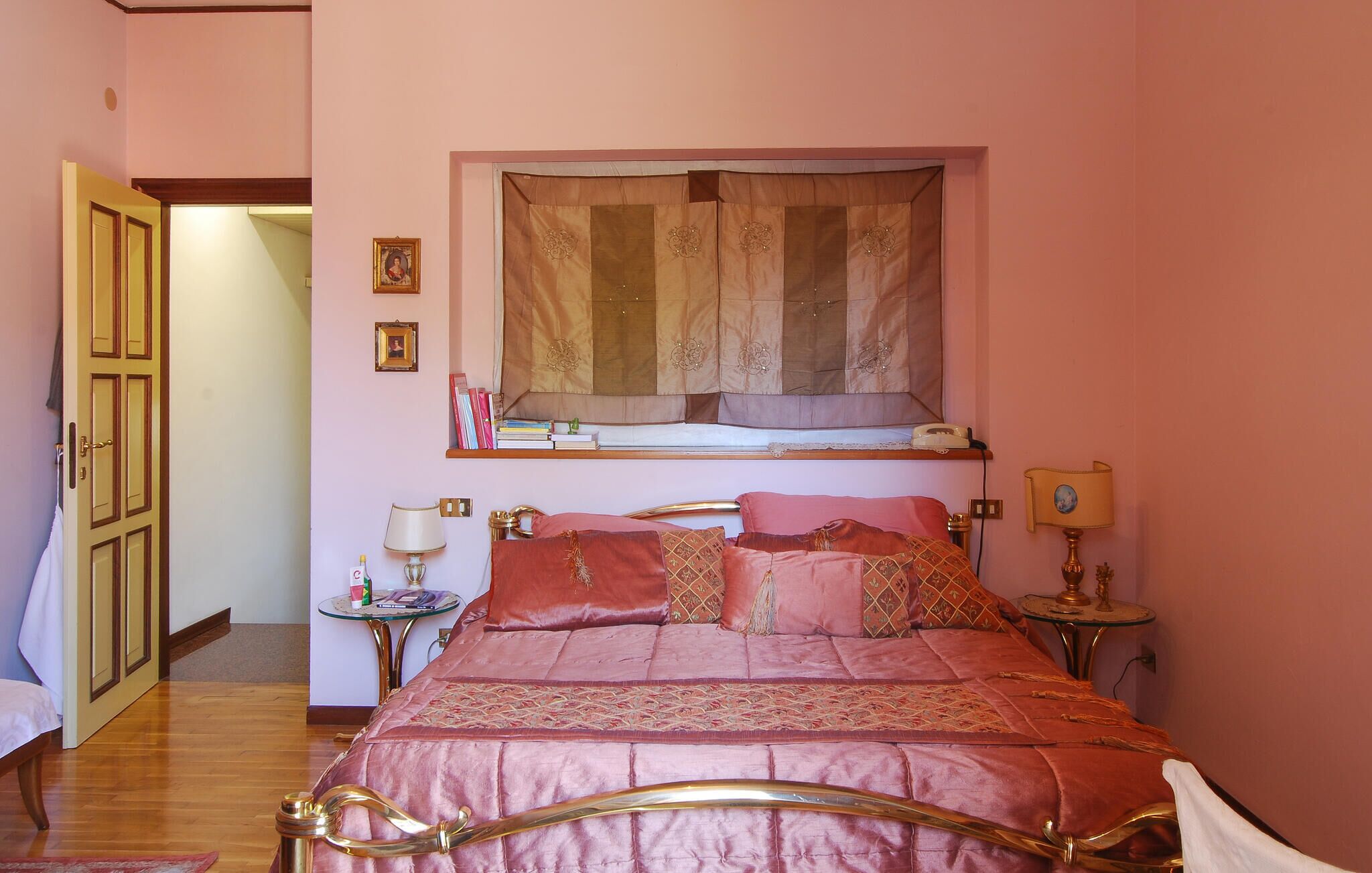 A bedroom with a bed, bedside tables, a window with curtains, and a door.