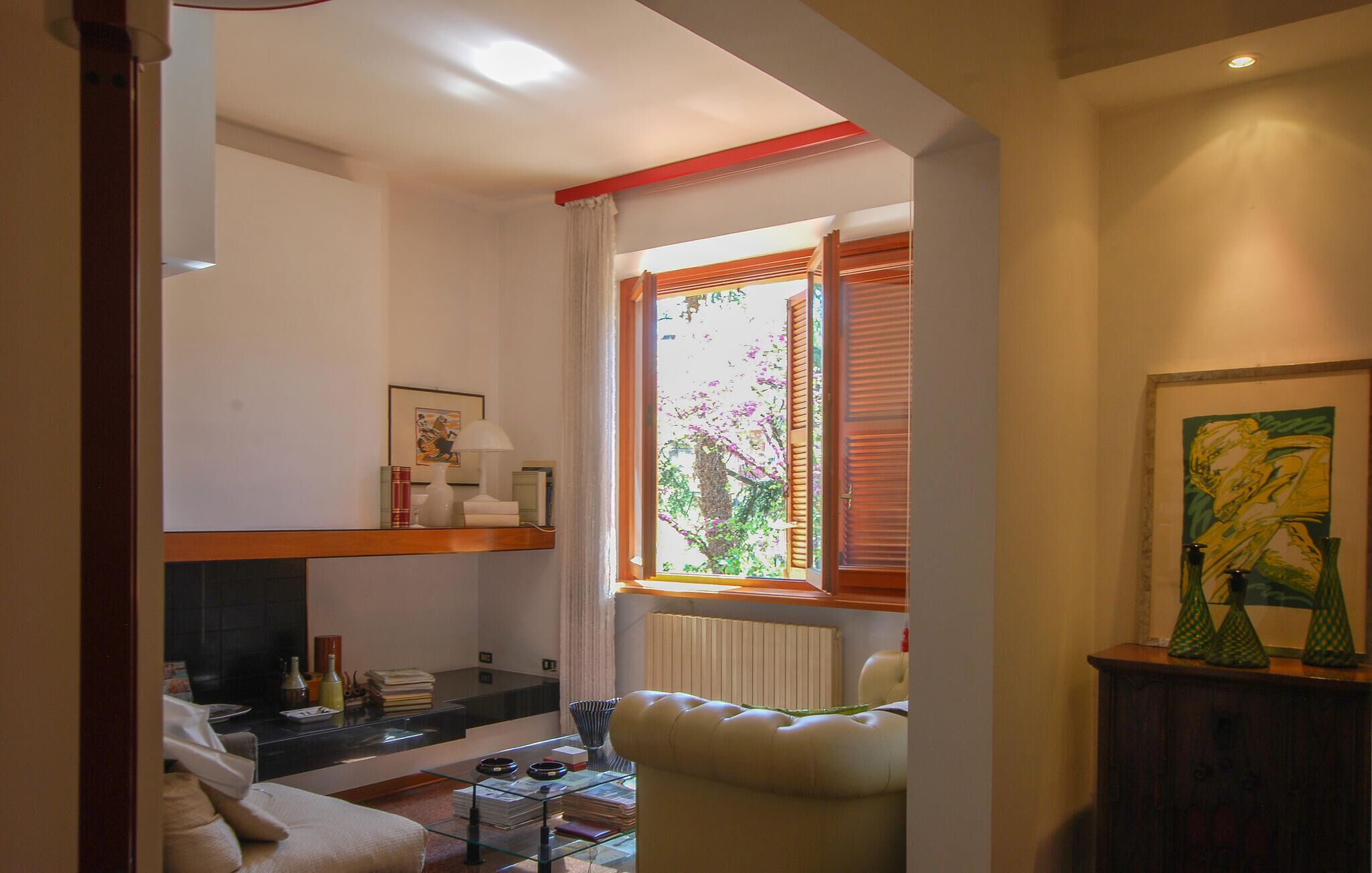 A living room with a sofa, a glass coffee table, a fireplace, and a window with blinds.