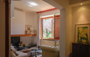 A living room with a sofa, a glass coffee table, a fireplace, and a window with blinds. - 3 bedroom stunning home in Appignano (Appignano)