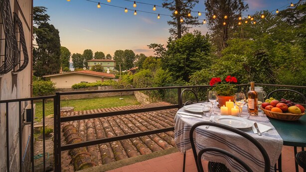 Eine Terrasse mit Esstisch, umgeben von viel Grün und Blick auf ein Haus.