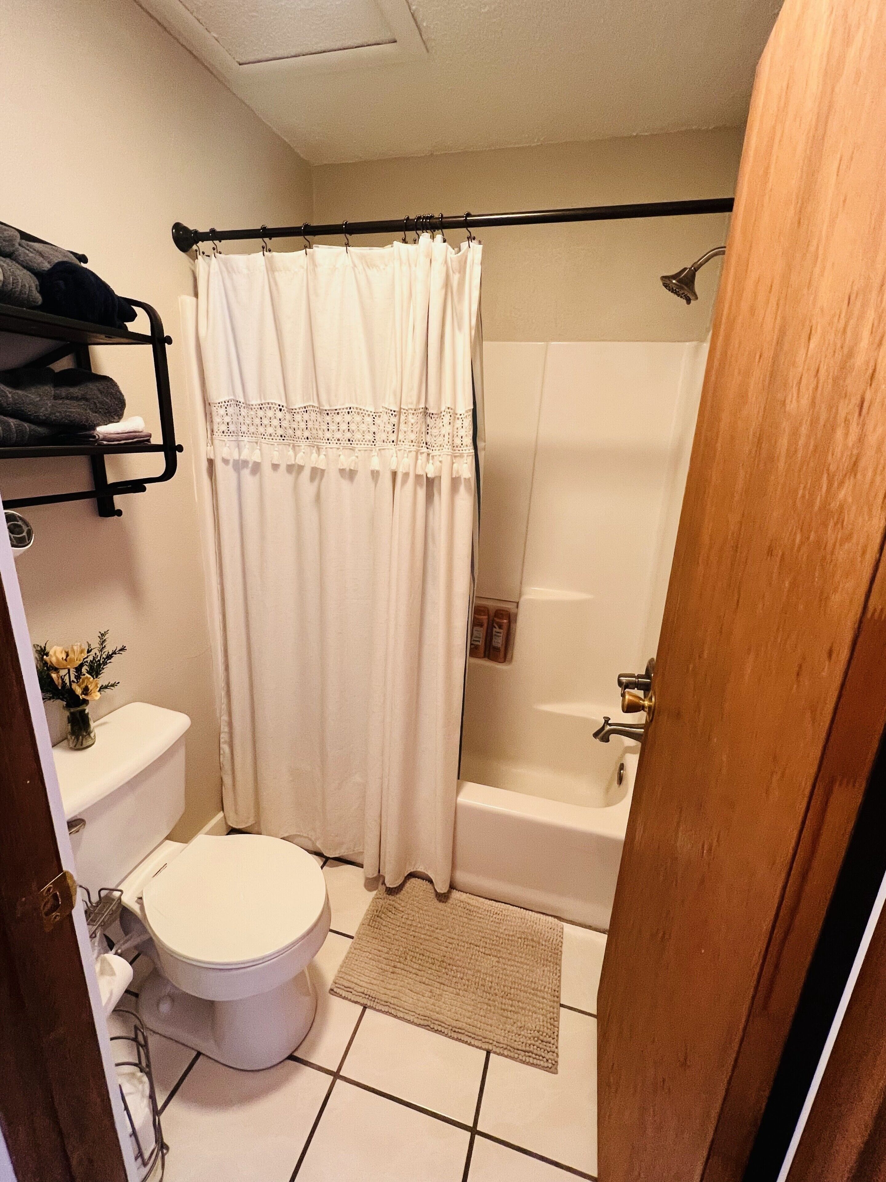 A bathroom with a toilet, a shower, a towel rack, and a shower curtain.