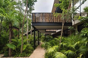 Un bâtiment moderne doté d’un espace extérieur abrité, entouré d’une végétation tropicale luxuriante.