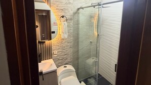 Un bagno moderno con box doccia in vetro, un water e un lavandino.