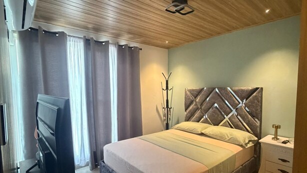 Camera da letto con un letto, una televisione, un comodino e una ventola a soffitto.