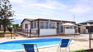Ein Haus mit Swimmingpool, zwei blauen Liegestühlen und einer Steinterrasse.