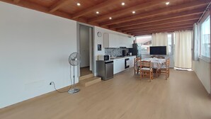 Eine moderne Küche mit weißen Schränken, einer Mikrowelle und einem Herd. Es gibt einen Essbereich mit Tisch und Stühlen, und eine Deckenventilatoren sind in der Ecke angebracht.