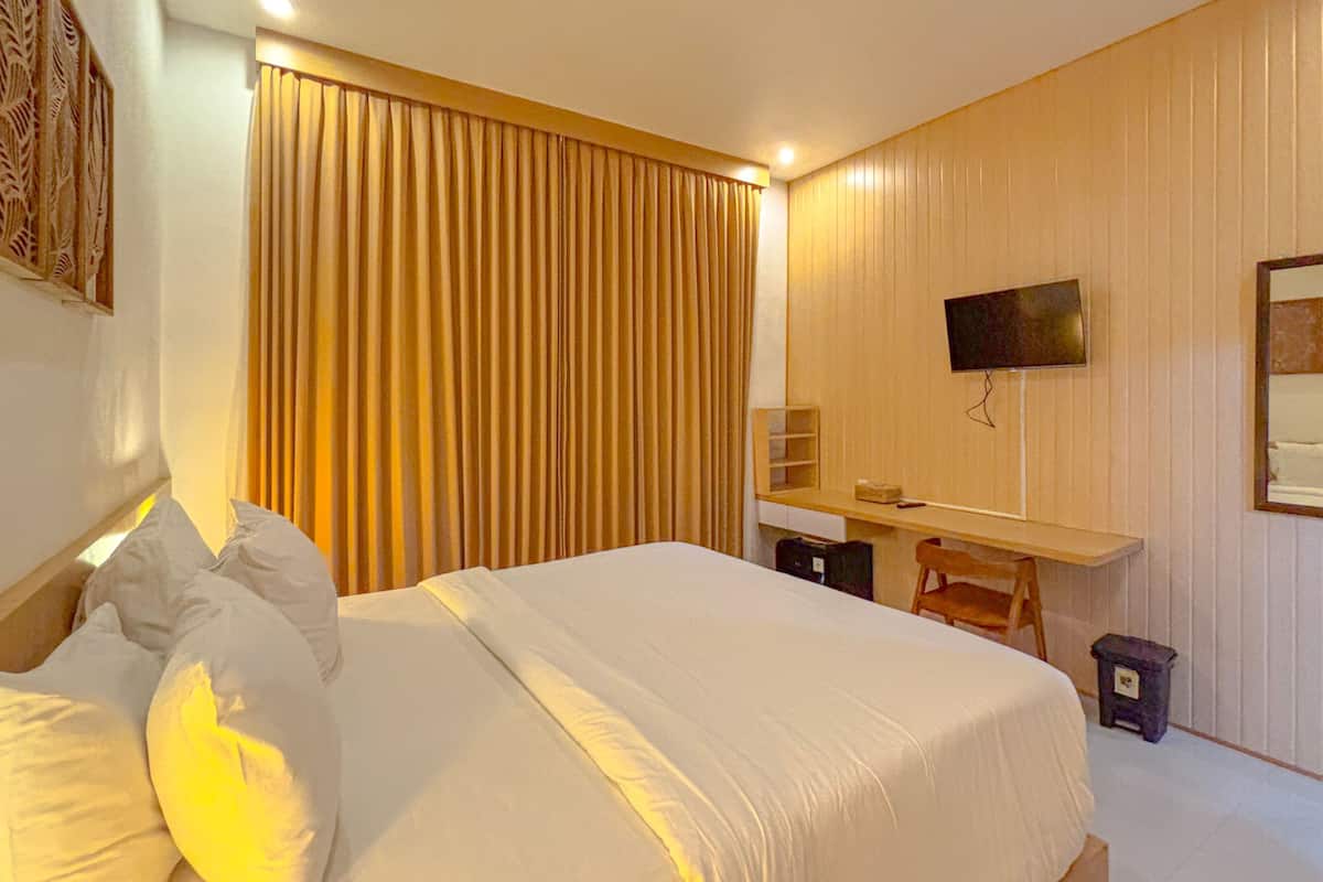 A hotel room with a bed, a desk, a chair, a television, and a mirror.