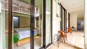 A hotel room with a balcony, a bed, a seating area with chairs, and a small table.