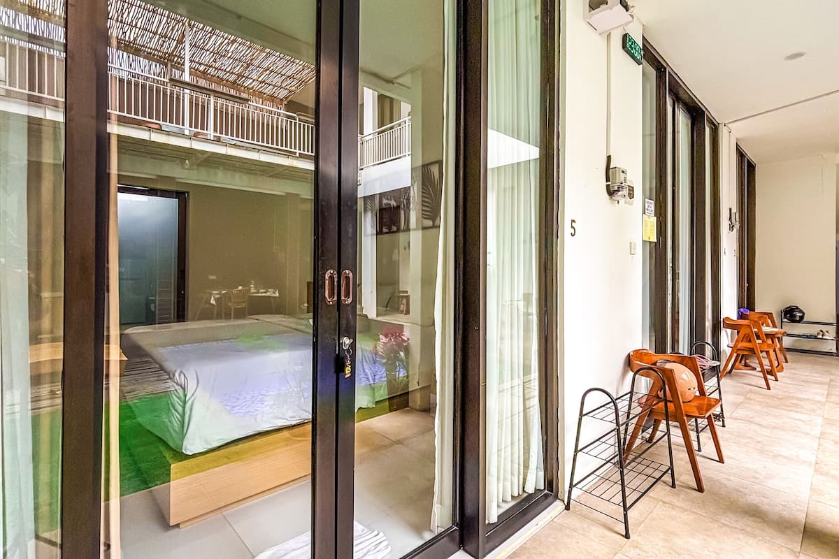 A hotel room with a balcony, a bed, a seating area with chairs, and a small table.