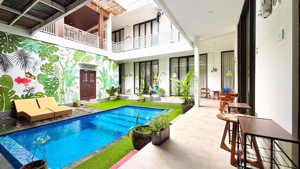 A pool area with a mural, a small lawn, and seating arrangements.