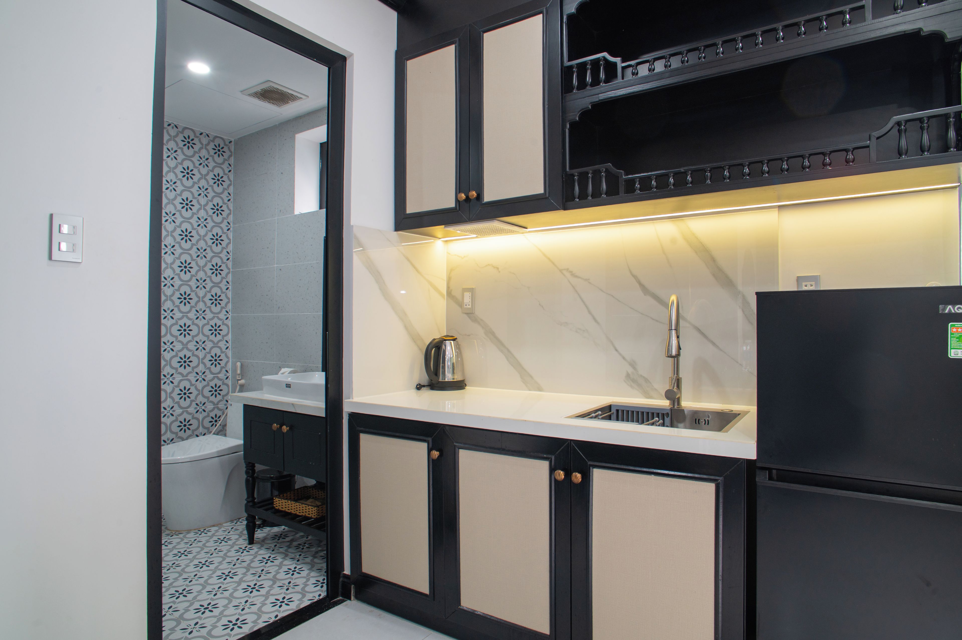 Cocina compacta con un lavamanos, hervidor y refrigerador.