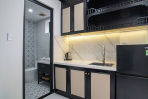 Cocina compacta con un lavamanos, hervidor y refrigerador.