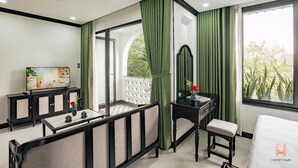 Habitación de hotel con balcón, televisor, escritorio, silla y cama.