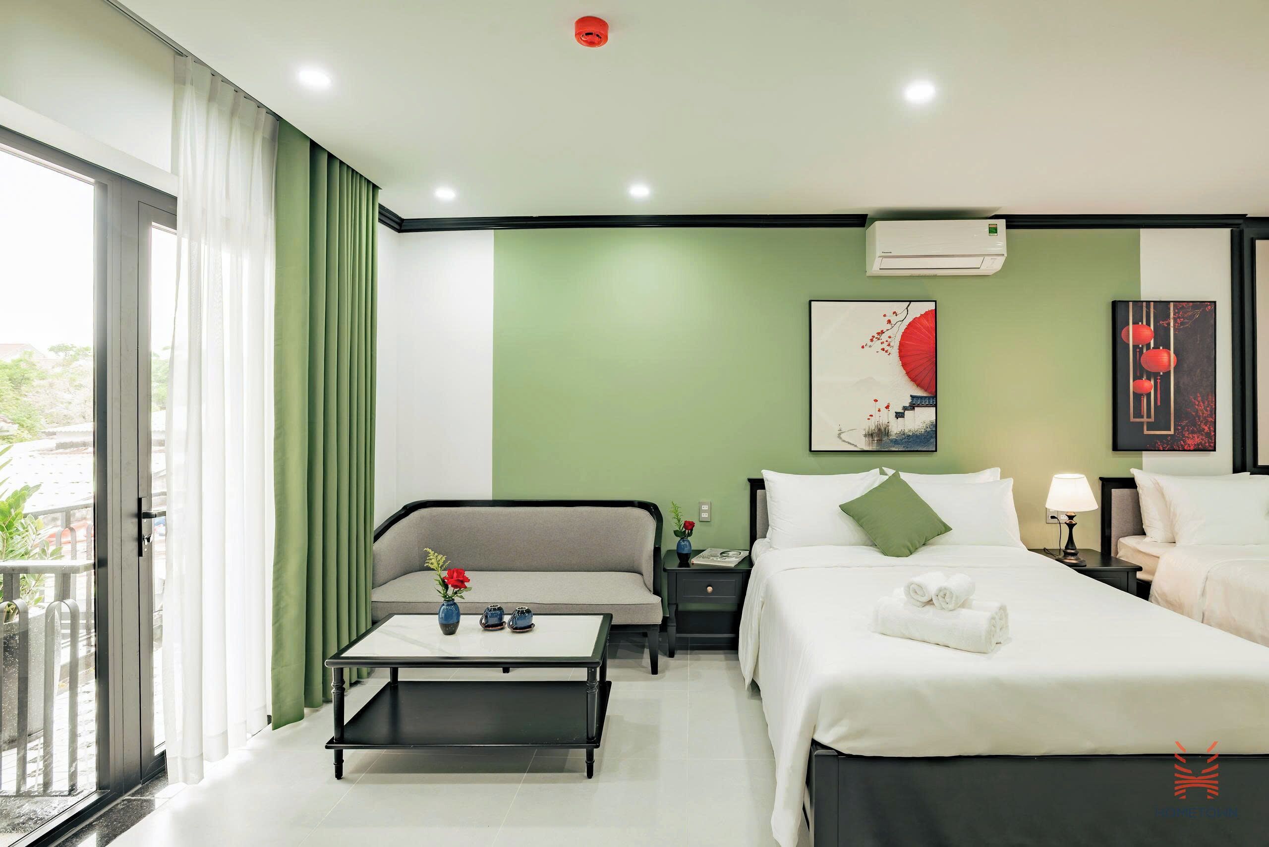 A hotel room with a bed, a sofa, a nightstand, a table, and a window with curtains.