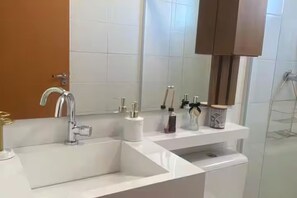 A bathroom with a white sink, a mirror, and a shower area. - Vrbo Property (Porto Alegre)