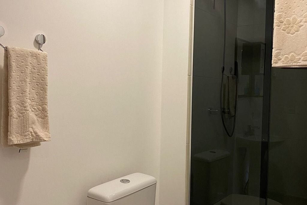 Une salle de bain avec des toilettes, une douche en verre et une serviette accrochée au mur.