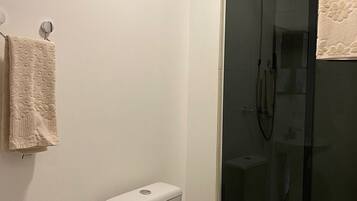 Une salle de bain avec des toilettes, une douche en verre et une serviette accrochée au mur.