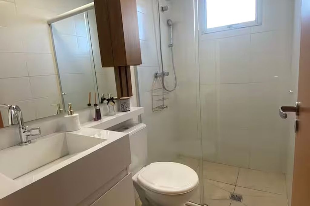 A bathroom with a white sink, mirror, and toilet.