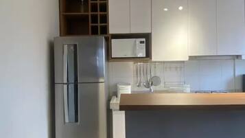 Une cuisine moderne avec un réfrigérateur en acier inoxydable, des armoires blanches et un plan de travail en bois.