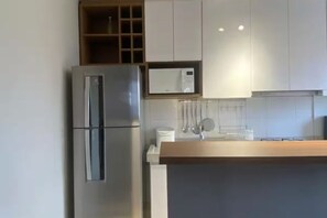 A modern kitchen with a stainless steel refrigerator, white cabinets, and a wooden countertop. - Vrbo Property (Porto Alegre)