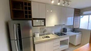 A modern kitchen with white cabinets, a stainless steel refrigerator, a microwave, and a sink.