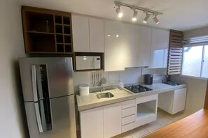 A modern kitchen with white cabinets, a stainless steel refrigerator, a microwave, and a sink. - Vrbo Property (Porto Alegre)