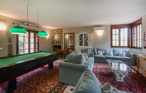 A pool table, sofa, and a billiards table in a room with a patterned carpet and a fireplace. - Amazing home in Monsagrati (Monsagrati)
