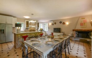 A spacious kitchen with a dining area set for a meal, featuring a stone backsplash, modern appliances, and a fireplace. - Amazing home in Monsagrati (Monsagrati)