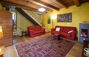 A living room with a wooden staircase, red sofas, a patterned rug, and a fireplace. - 3 bedroom awesome home in Porzano (Porzano)