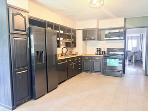 A modern kitchen with a refrigerator, stove, microwave, and a sink.