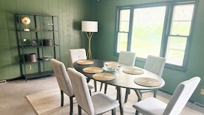 Un coin repas avec une table ronde, six chaises, un globe terrestre posé sur une étagère et une lampe.