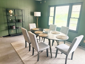 A dining area with a round table, six chairs, a globe on a shelf, and a lamp.