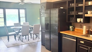 Une cuisine moderne avec un réfrigérateur noir, un plan de travail en bois et un coin repas comprenant des chaises et une table.
