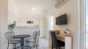 Una cocina compacta con comedor, un televisor montado en la pared y un globo en el escritorio.