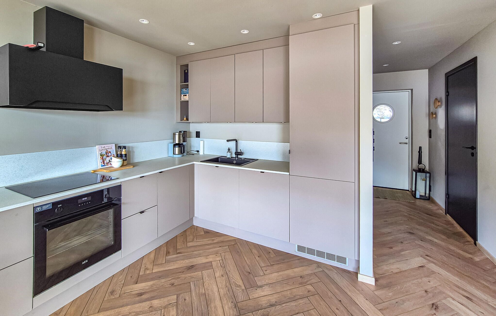 A modern kitchen with a built-in oven, a coffee maker, and a sink.