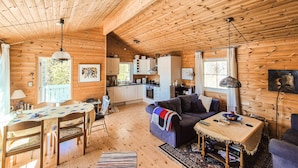 Ein Ferienhaus-Interieur mit Essbereich, einer Couch, einer Küche und Holzwänden.