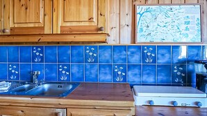 A kitchen with wooden cabinets, a blue tiled backsplash, a sink, and a stove. - Cozy home in Vøringsfoss with sauna (Vøringsfoss)