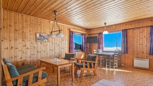 A wooden cabin interior with a dining area, chairs, a table, a TV, and a view of the outdoors. - Cozy home in Vøringsfoss with sauna (Vøringsfoss)