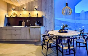 A modern kitchen with wooden cabinets, a round dining table with chairs, and a pendant light. - 4 bedroom beautiful home in Vøringsfoss (Vøringsfoss)