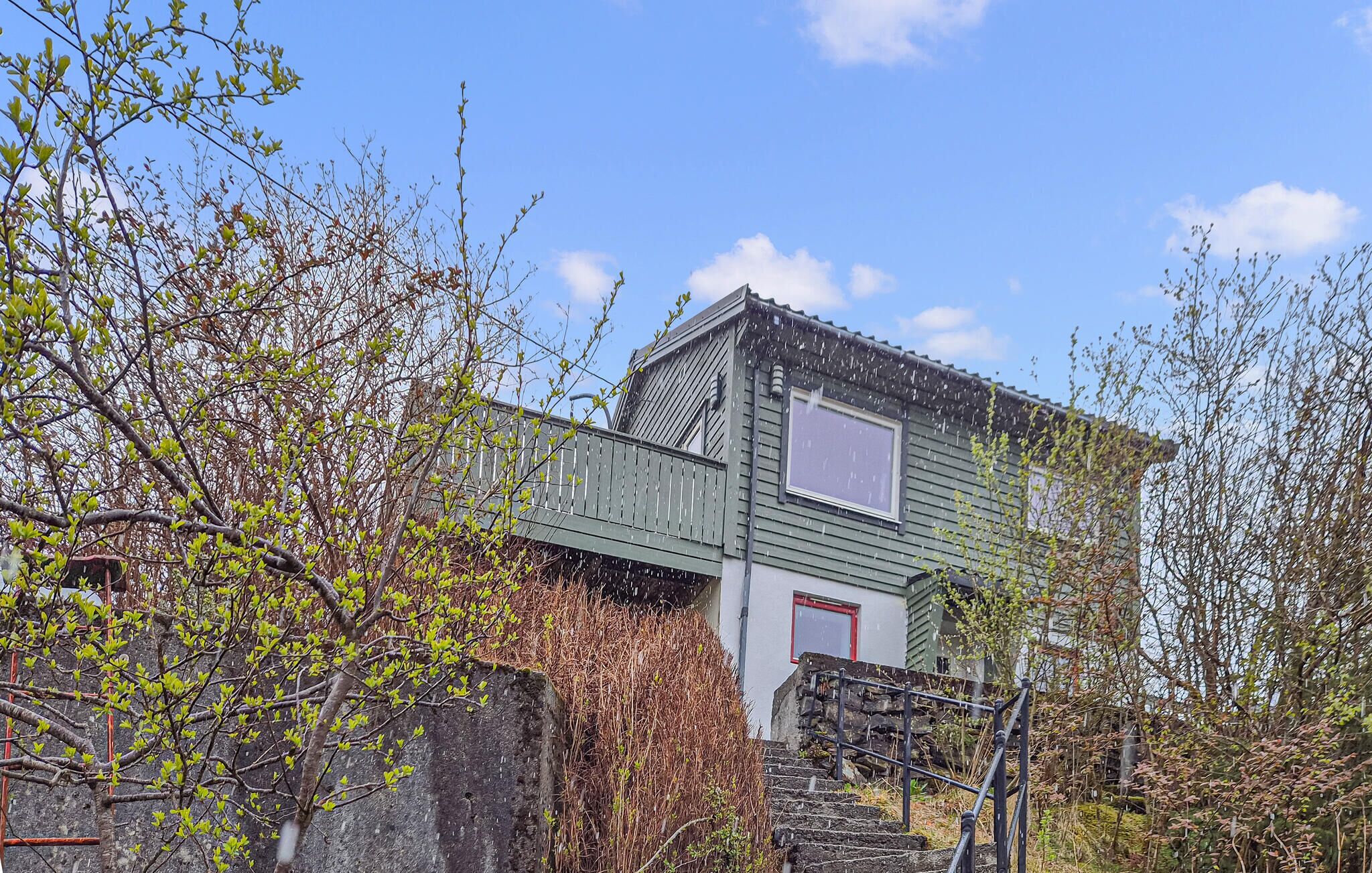 Une maison à deux étages avec un balcon, une fenêtre et une porte rouge.