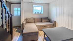 Een kamer met een bank, een tafel, een raam met uitzicht en een deur.