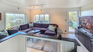Een moderne woonkamer met een hoekbank, een glazen salontafel en een televisie.