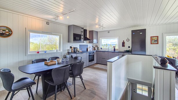Een moderne keuken met een eethoek, houten vloeren en grote ramen.