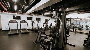 A gym with treadmills, weight machines, and a mirrored wall. - Oceanfront Terrace Apartment - Steps to Beach (Carolina)